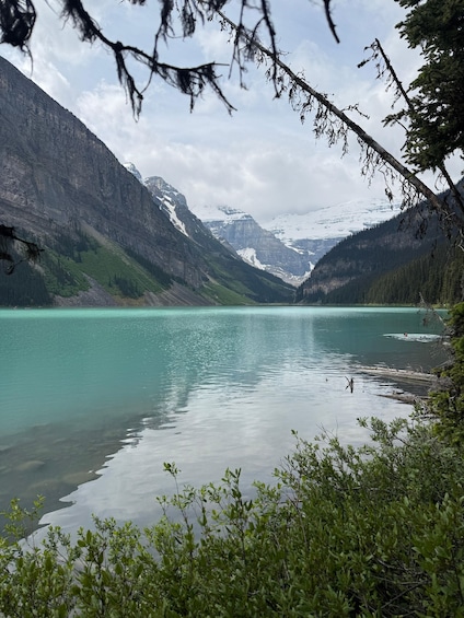 A mountain lake surrounded by forested slopes and snow-capped peaks. 4