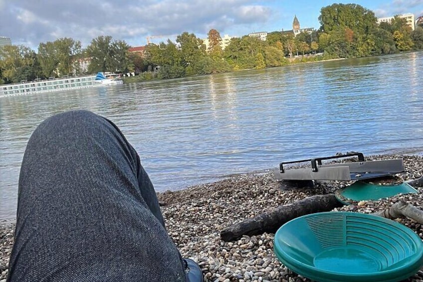 A lakeside view with a boat, pebbles, and a green container. 4