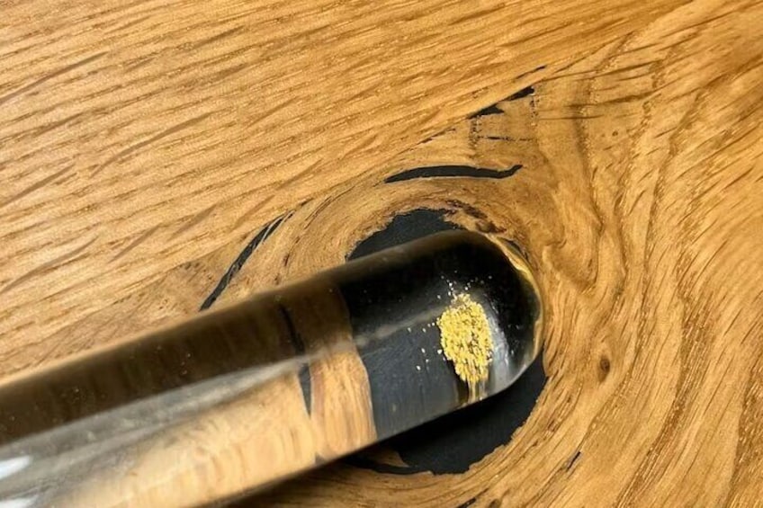 A close-up of a wooden surface with a dark stain and a small pile of yellow substance. 2