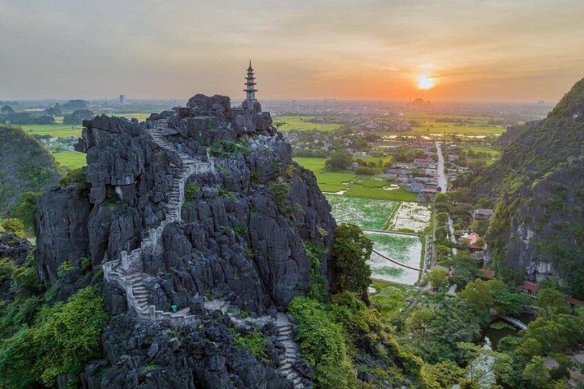 Eine gebirgige Landschaft mit einem Tempel auf dem Gipfel, einem gewundenen Pfad und einem Sonnenuntergang in der Ferne. 5