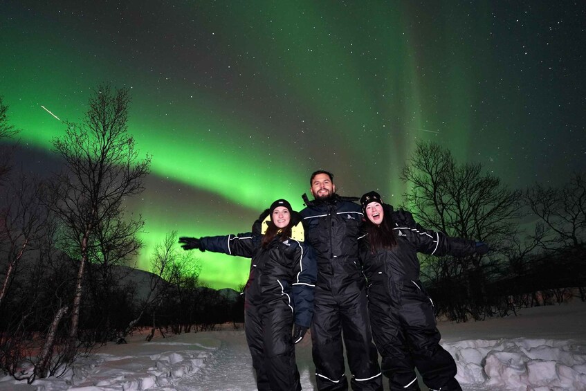 A group of people posing with their arms outstretched under the aurora borealis. 4