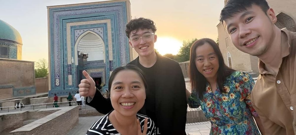 A group of people posing in front of a historic building with a large archway. 2