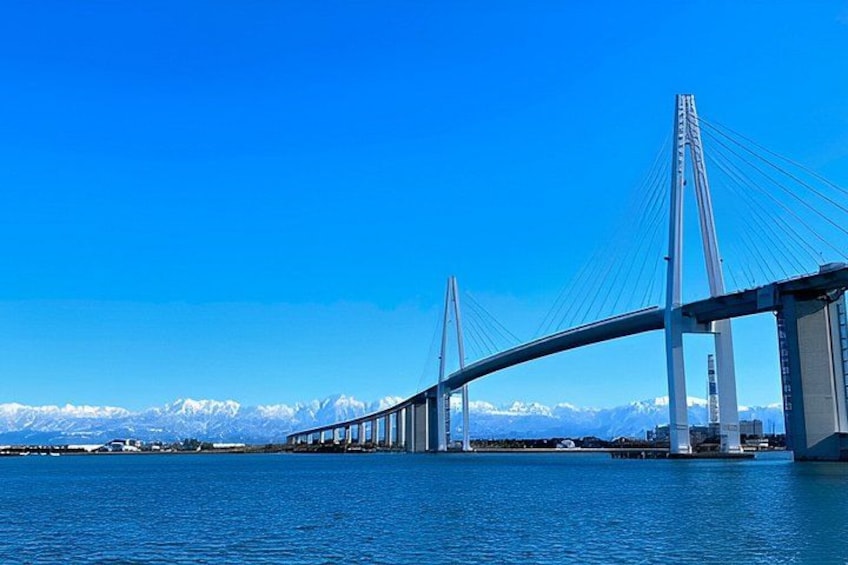 A suspension bridge over a body of water with mountains in the background. 4
