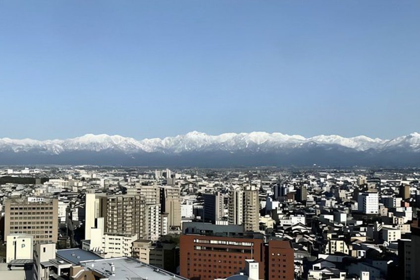 A cityscape with buildings and snow-capped mountains in the background. 2