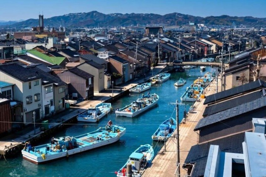 A coastal town with narrow waterways, boats docked along the sides, and traditional buildings. 5