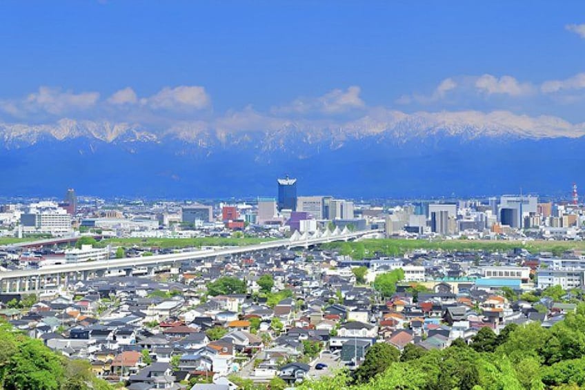 A cityscape with a bridge, buildings, and mountains in the background. 1