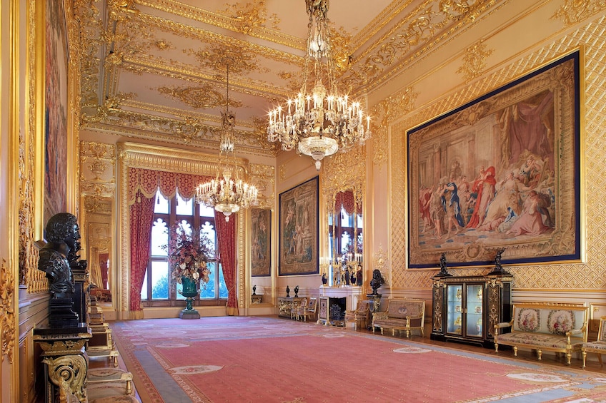 An opulent room with gold accents, a large chandelier, and classical paintings. 4
