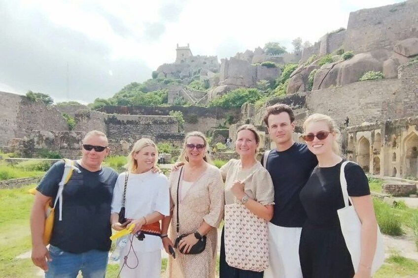 Eine Gruppe von Menschen steht vor einer alten Steinarchitektur, im Hintergrund ist ein Schloss zu sehen. 4
