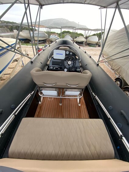 A boat's interior with a steering wheel, dashboard, and cushioned seats. 5