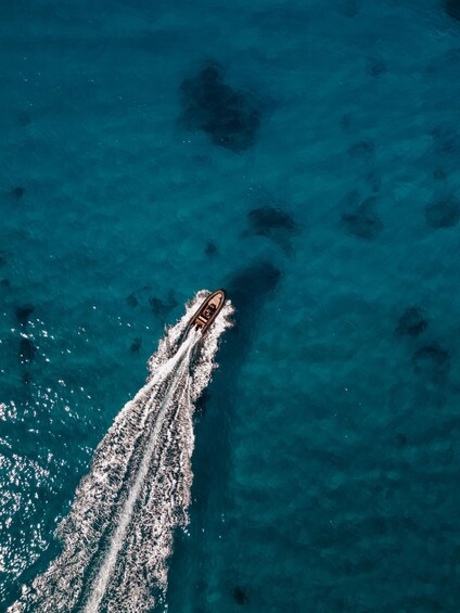An aerial view of a boat creating a wake in turquoise water. 4