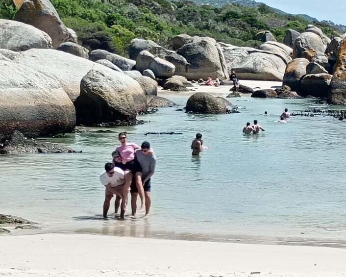 A river with large rocks and people swimming and standing in the water. 1