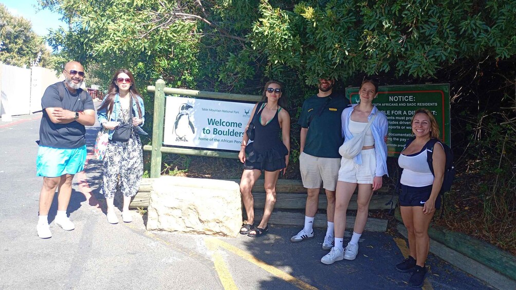 A group of people standing in front of a sign welcoming visitors to Table Mountain National Park. 4