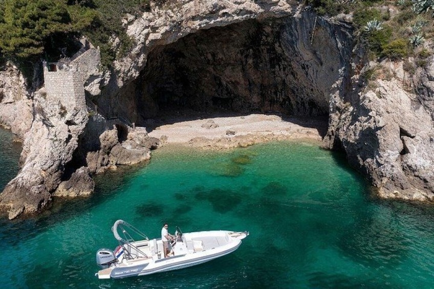 A boat near a rocky coastline with a cave-like formation. 5
