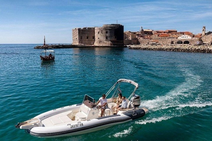 A motorboat on a calm sea with a historic fort in the background. 3