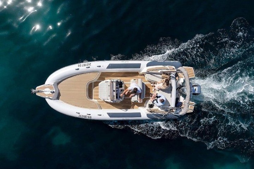 A white motorboat with a wooden deck and seating area, moving through a body of water. 4
