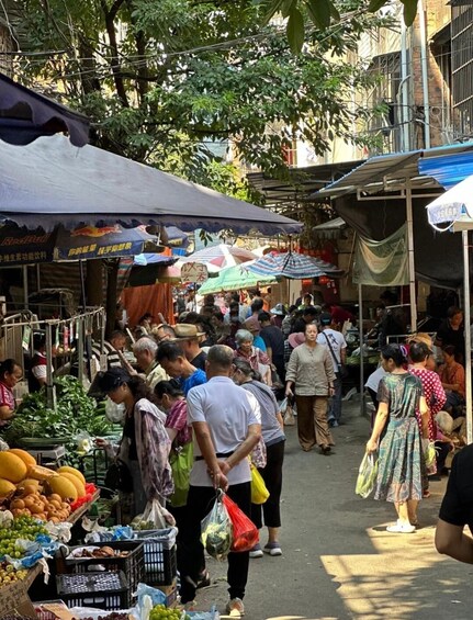 A bustling outdoor market with various stalls selling fruits and vegetables. 3