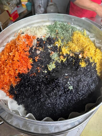 A metal colander with various colored rice grains. 2