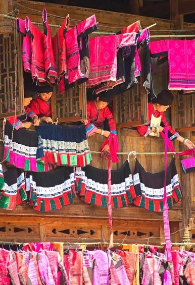 A person weaving colorful textiles on a wooden loom. 4
