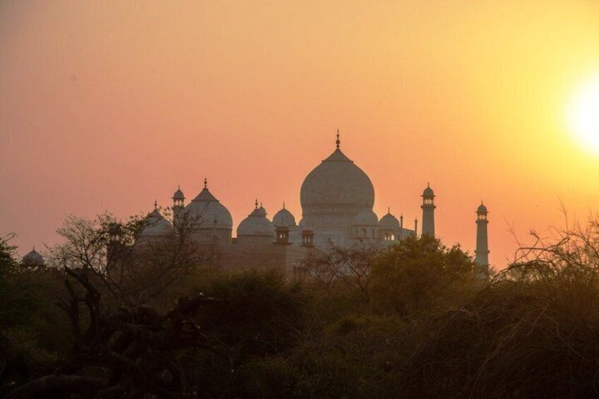 Taj Mahal i solnedgang, med kupler og minareter silhouetteret mod himlen. 2