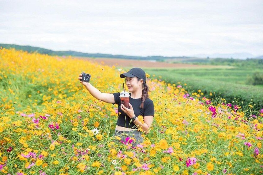 A person taking a selfie in a field of yellow flowers with a black cap and a black t-shirt. 5