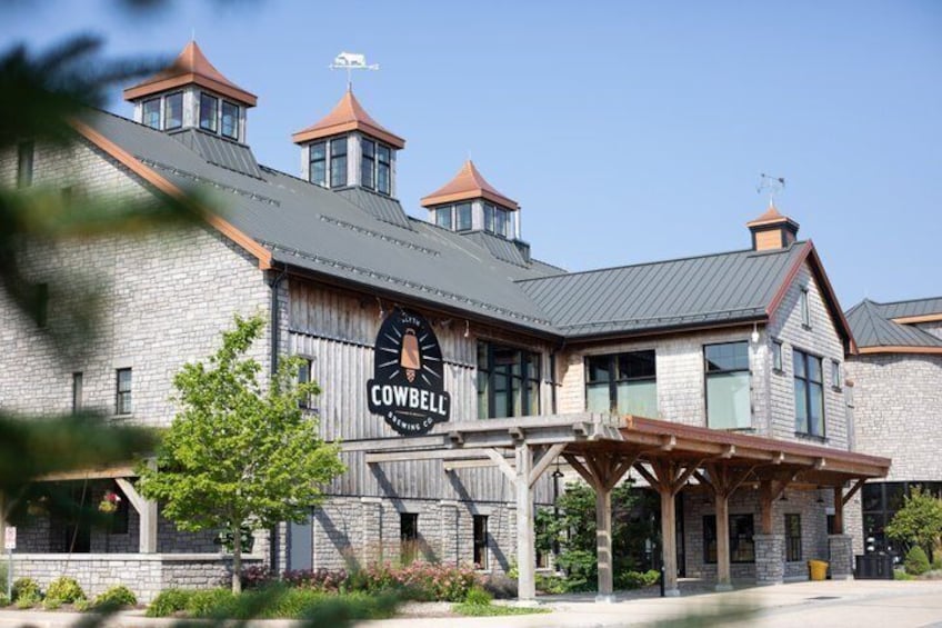 A building with a sign reading 'Cowbell Brewery Co.' and a covered outdoor seating area. 4