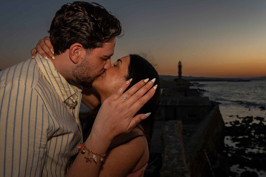 A couple embracing at sunset with a lighthouse in the background. 3