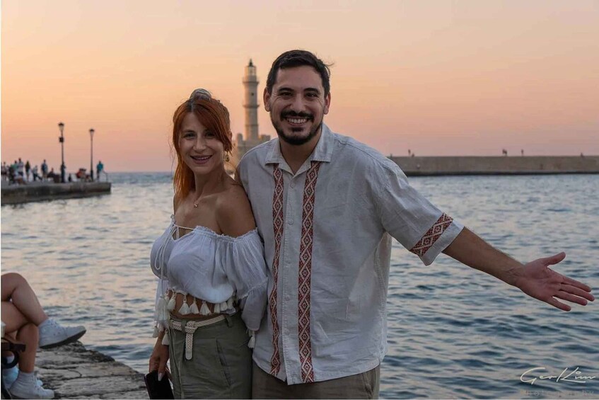 A couple standing by a waterfront with a lighthouse in the background. 4