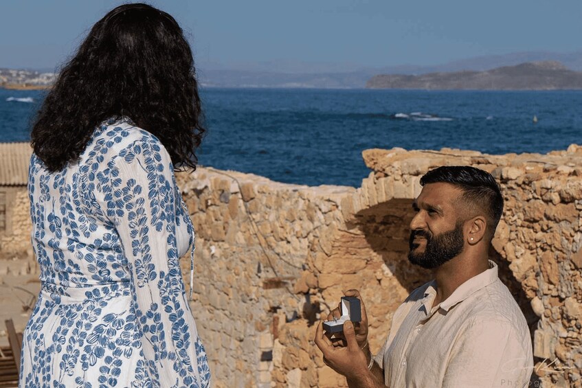 A couple by a rocky coastline with the sea in the background. 5