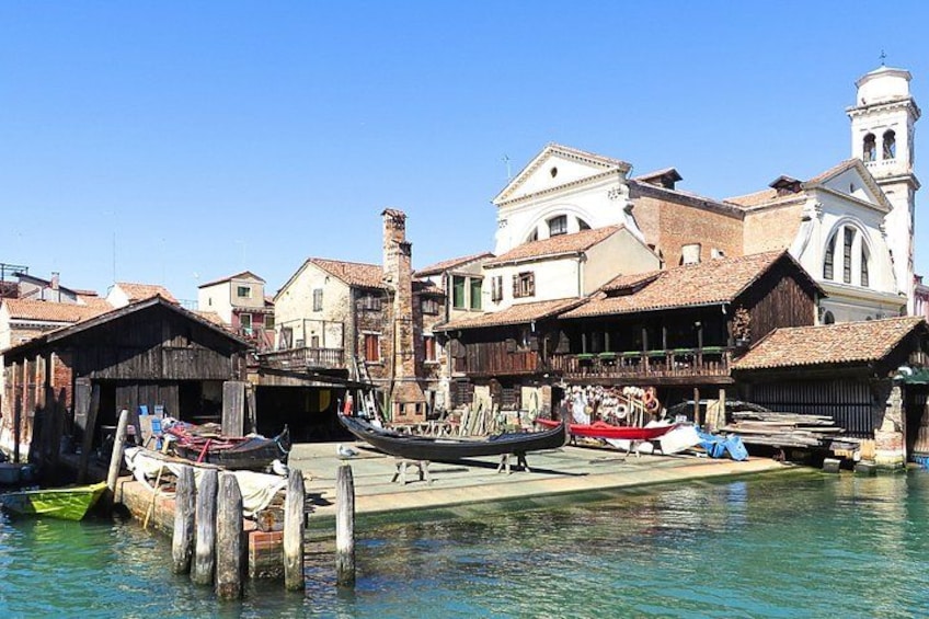 A canal with boats, wooden buildings, and a church tower. 3