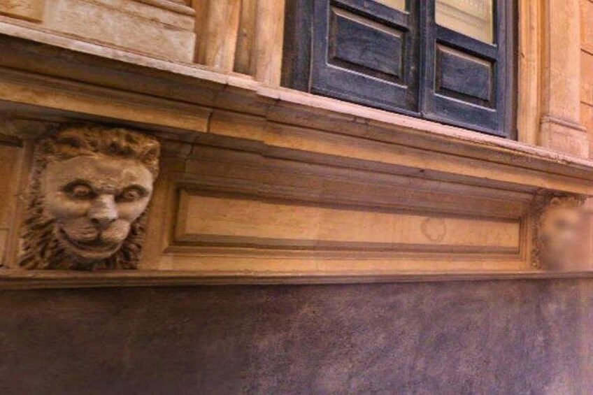 A stone lion head sculpture on a building facade. 3