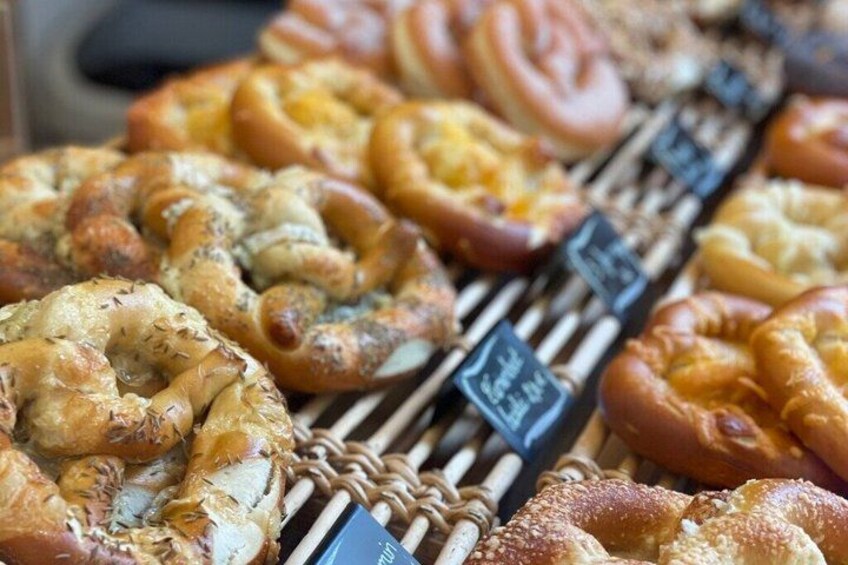 An assortment of baked goods, including braided and twisted breads, displayed on a rack. 2
