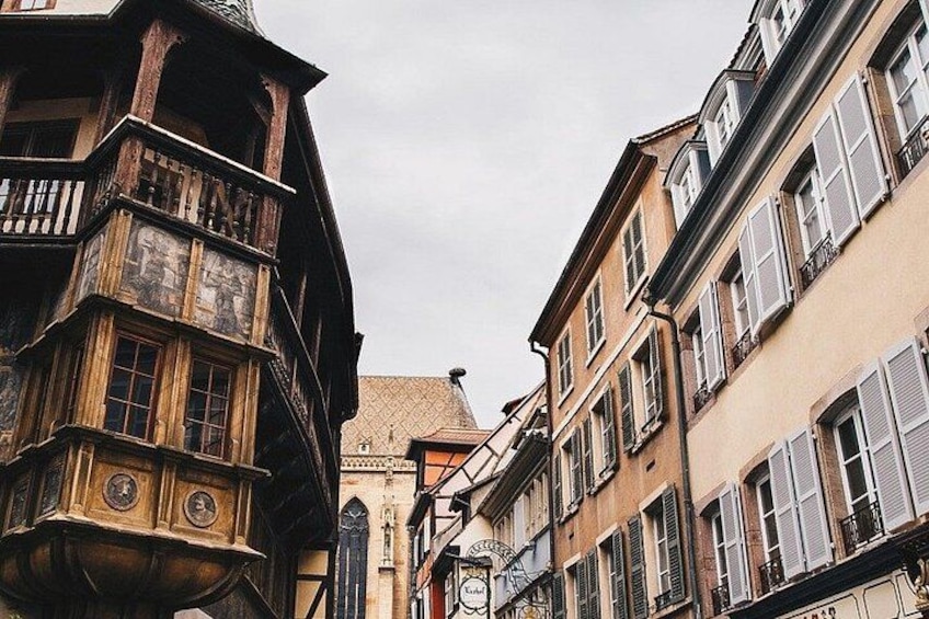 Une rue étroite bordée de vieux bâtiments, une tour de l’horloge et une enseigne représentant un lion. 2