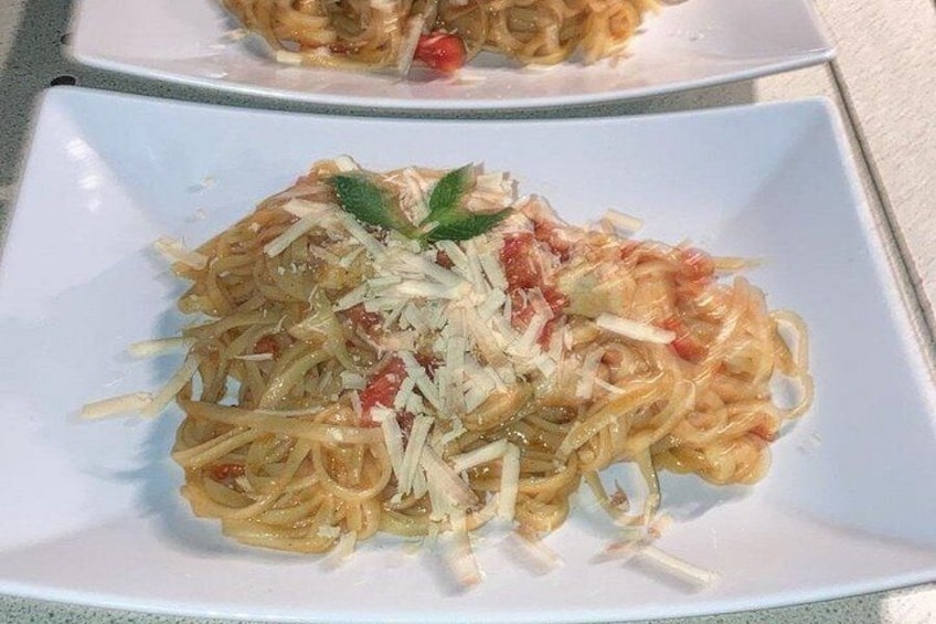 Une assiette de spaghettis à la sauce tomate, recouverte de fromage râpé et garnie d’une feuille de basilic. 3