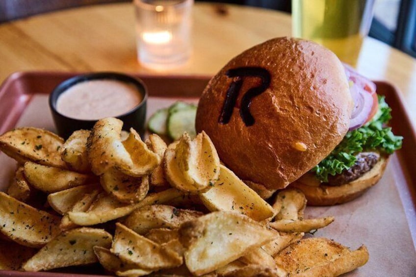 Una hamburguesa con una letra 'R' en el pan, una guarnición de papas fritas sazonadas y un pequeño recipiente con salsa. 3
