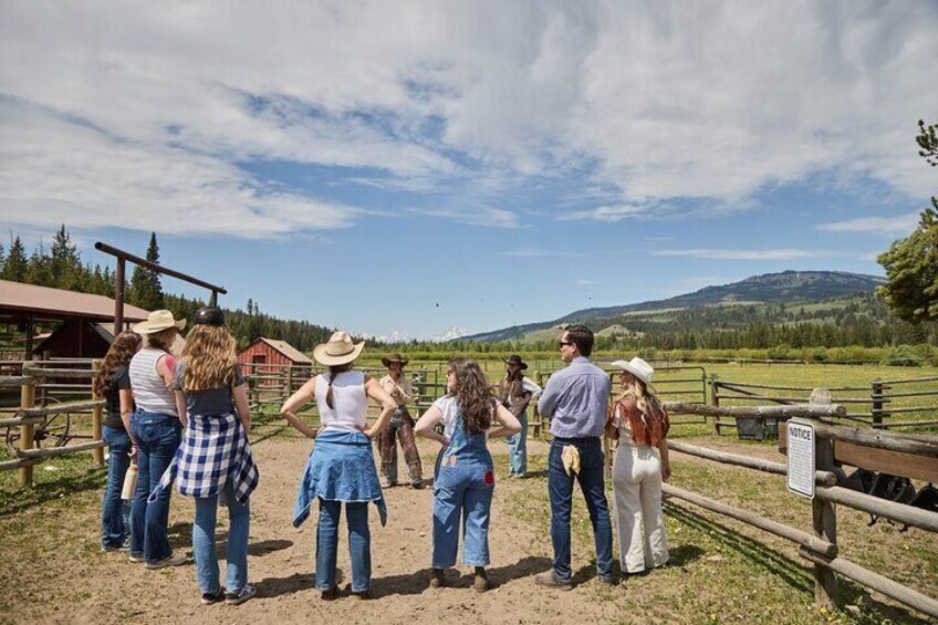 A group of people standing in a fenced area with a mountainous landscape in the background. 4