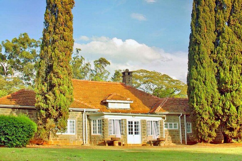 A stone house with a tiled roof, surrounded by tall trees and a grassy lawn. 5