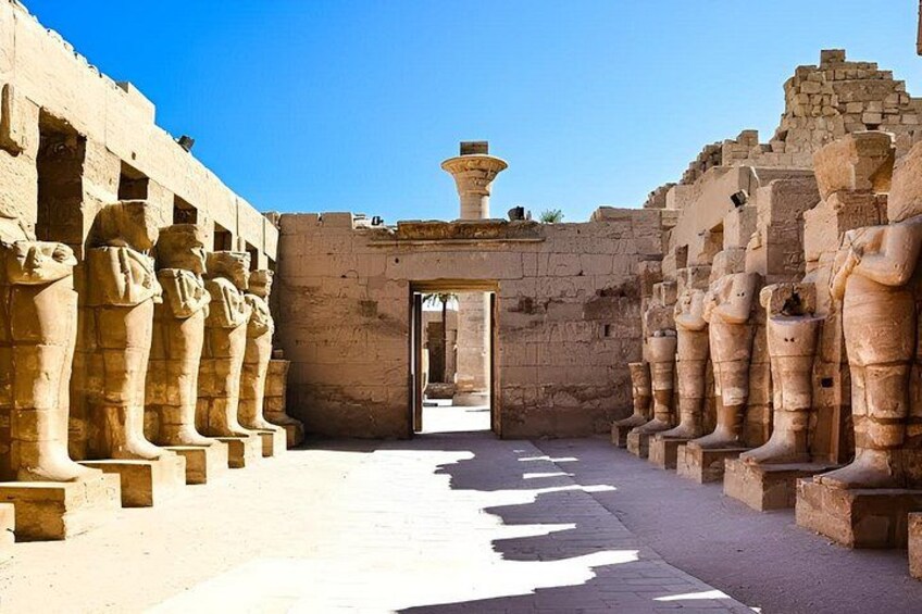 A corridor with statues on either side, leading to an open doorway. 5