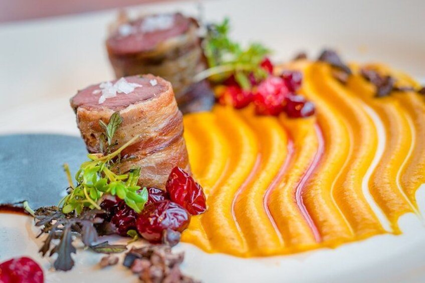 A plated dish with meat, sauce, and garnishes. 4