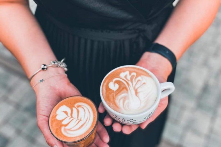 Two hands holding cups of coffee with latte art. 5