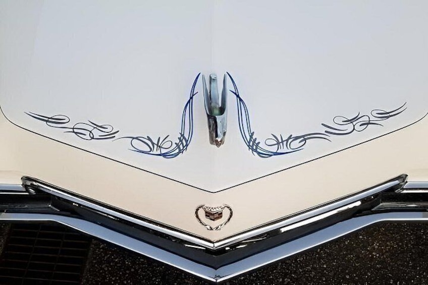 Le capot d’une voiture de collection, orné d’un emblème distinctif et de motifs décoratifs en spirale. 2