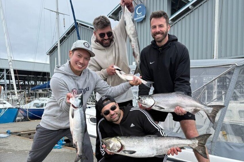 Four people holding fish, a boat, and a building with a sign. 4