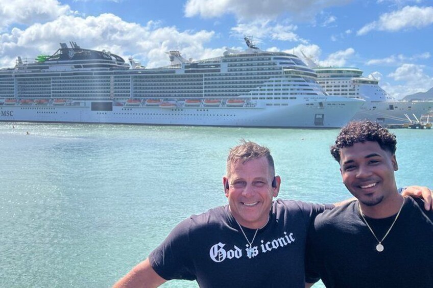 Two people in front of a large cruise ship with the MSC logo. 1