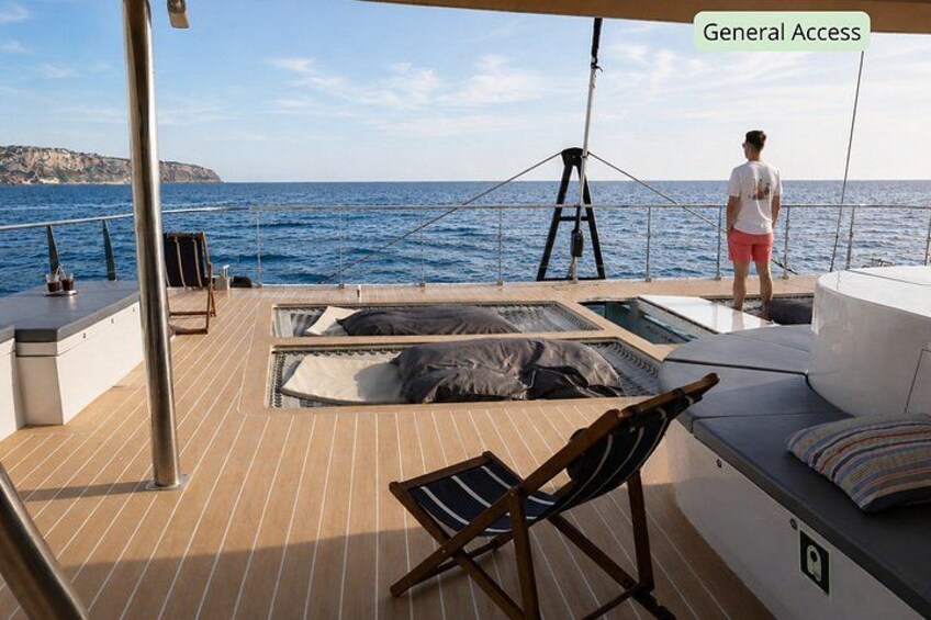 A deck with a hot tub, lounge chairs, and a person standing by the railing. 3
