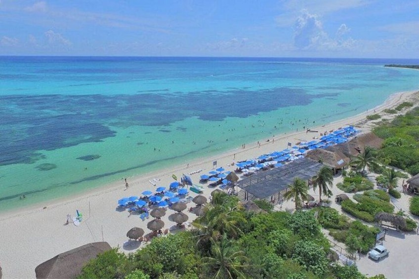 Una playa con agua turquesa cristalina, sombrillas azules y palmeras. 5