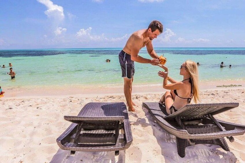 Una playa con dos sillas de descanso, un hombre y una mujer, y el océano al fondo. 4