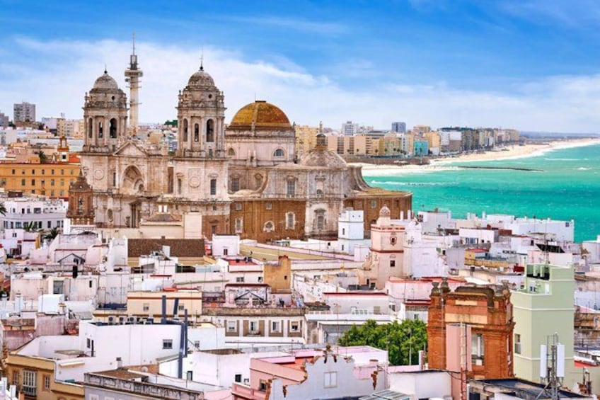 Un paysage urbain côtier avec une cathédrale imposante, une plage et des bâtiments urbains denses. 1