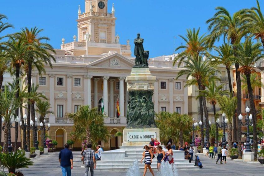 Une place agrémentée d’une statue, de palmiers et d’un bâtiment à colonnes. 4