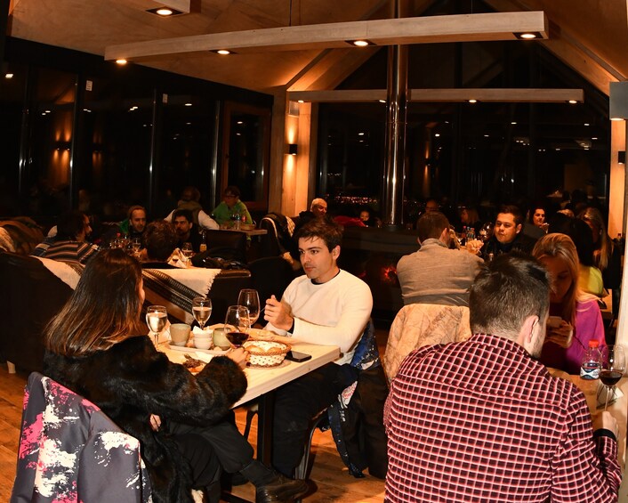 A group of people dining at a restaurant with tables set for meals. 3
