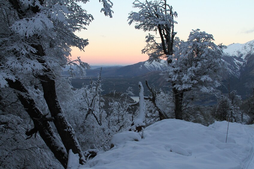 A snow-covered mountain landscape with trees and a sunset in the background. 5