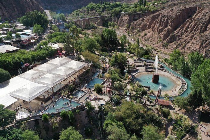 A hot spring resort with pools, a large covered area, and a mountainous backdrop. 5